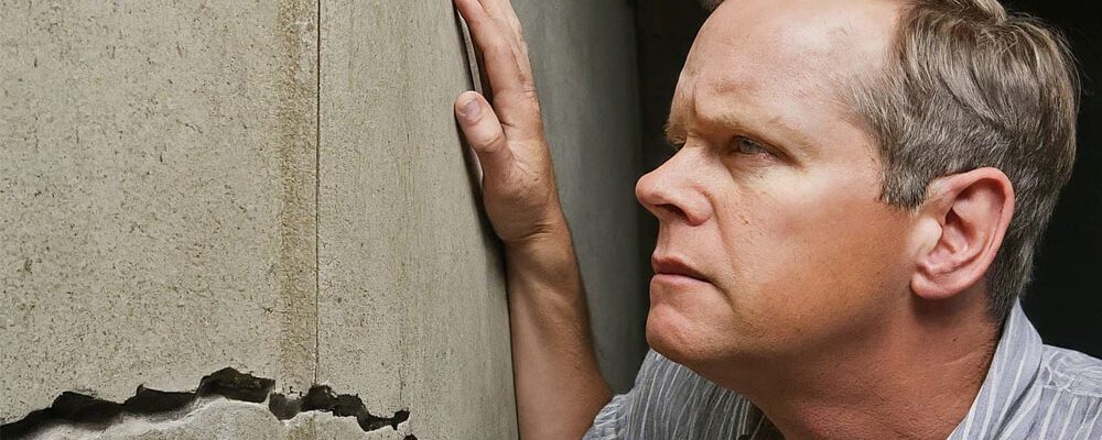 Image of man checking a crack in his basement wall.