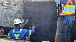 Image of Shield Foundation Repair employees spraying an application of WetSuit waterproofing product.