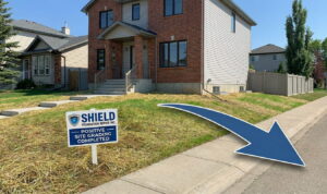 Professional positive site grading by Shield Foundation Repair Inc in an Edmonton residential neighborhood, showing re-seeded grass and a yard sloped away from the foundation to prevent water damage.