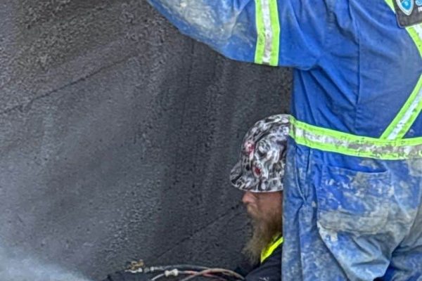 Image of Shield Foundation Repair employees spraying an application of WetSuit waterproofing product.
