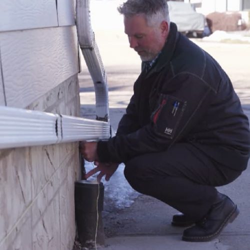 Image of a Shield foundation specialist inspecting a home exterior for damage
